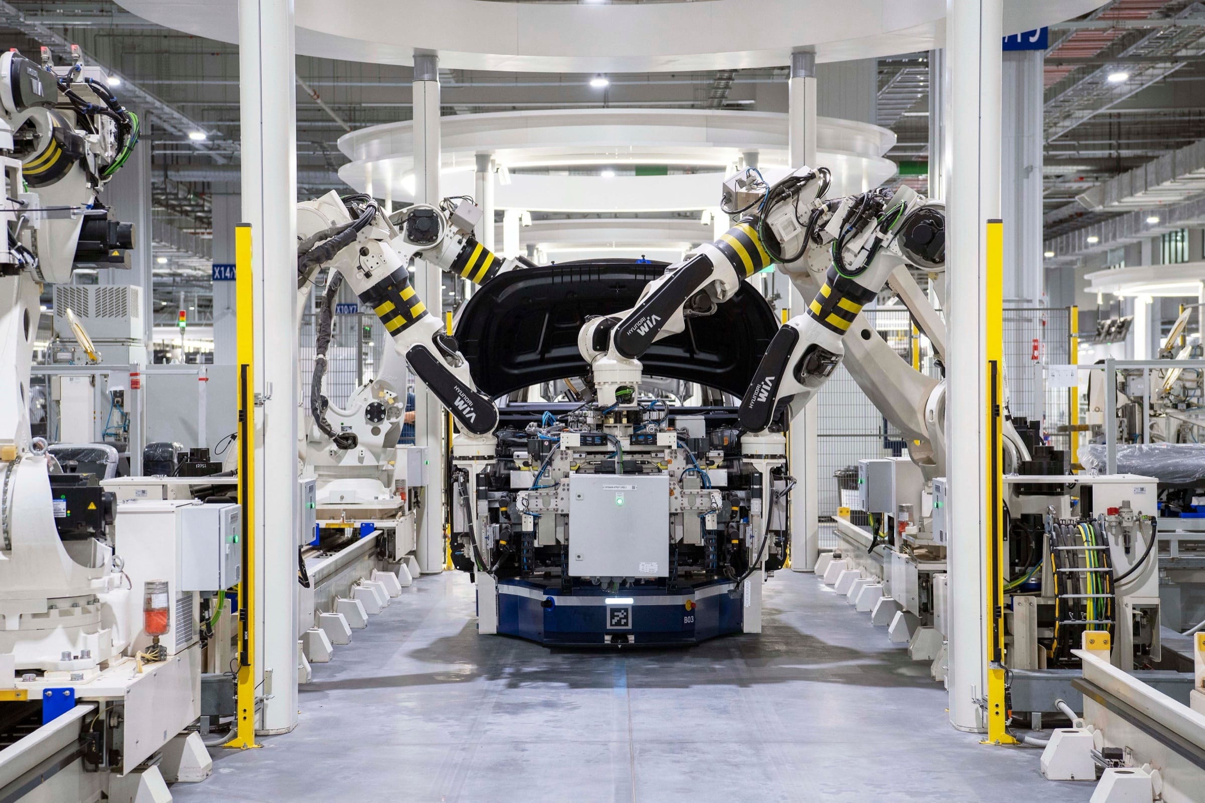 Robot arms working over a car body on an assembly line