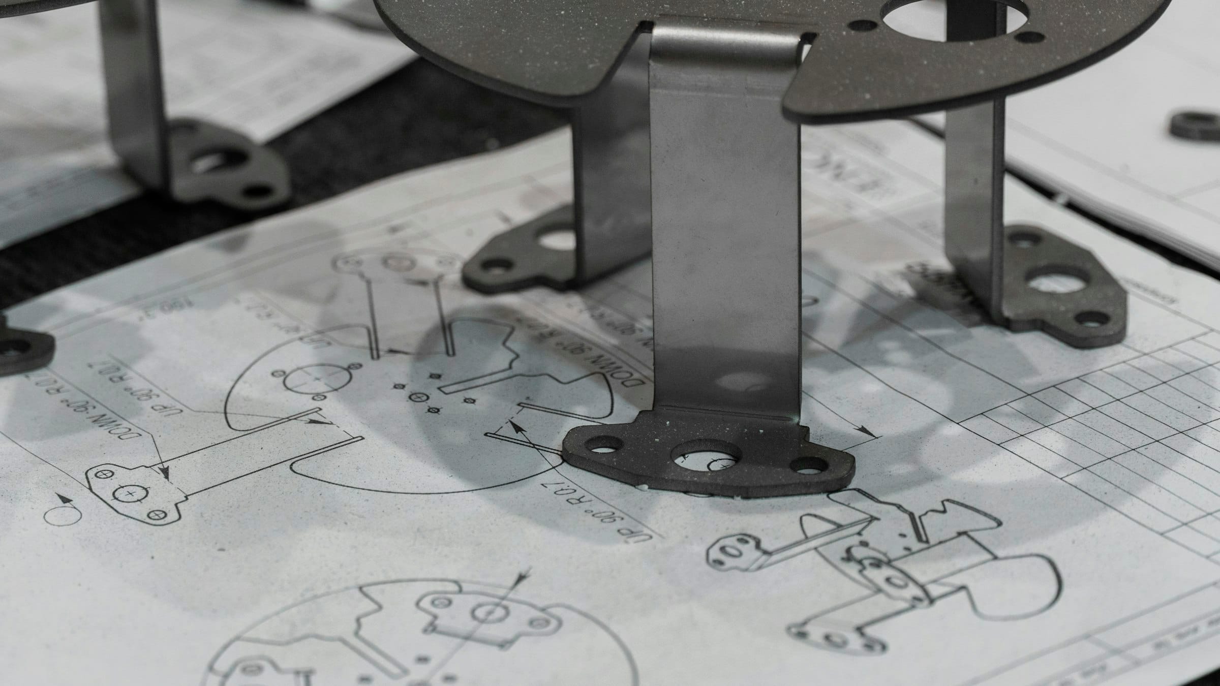 Bent sheet-metal parts standing on their technical drawings