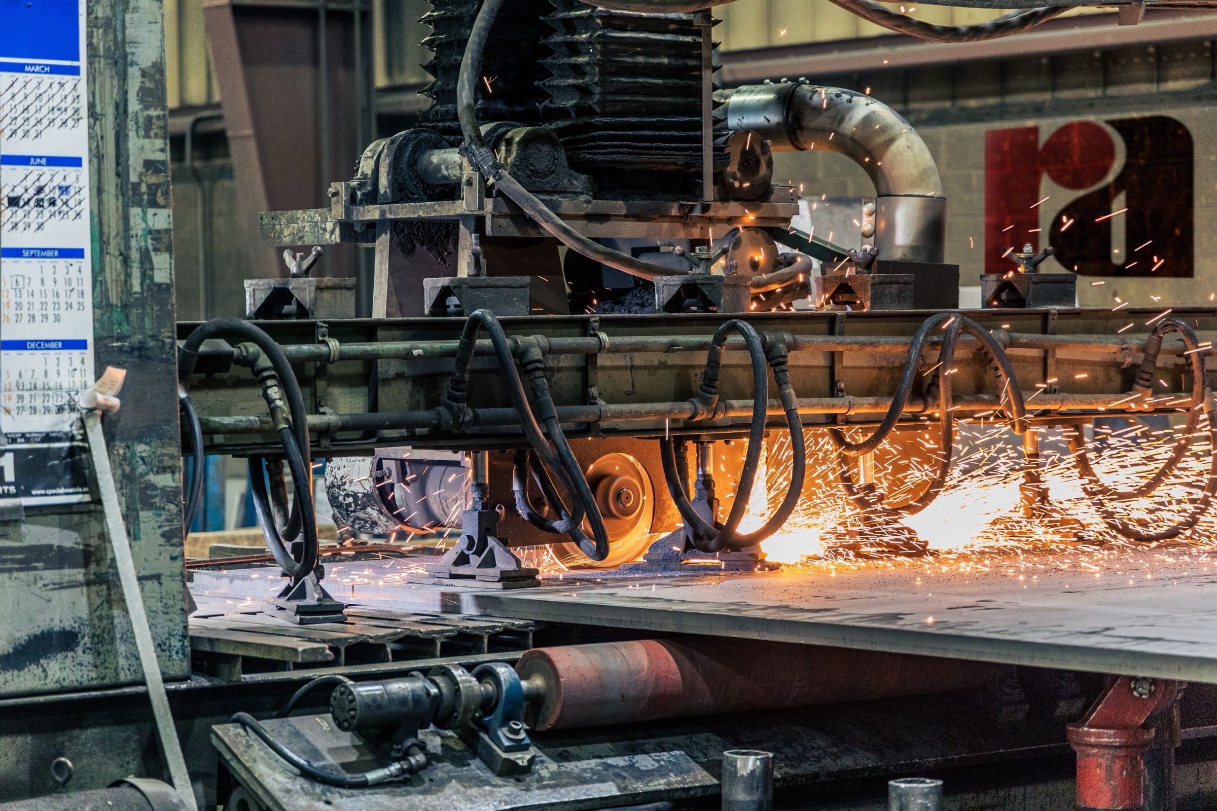 A cutting head working along a steel plate, sparks under the beam.